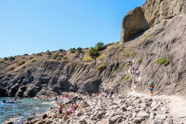 Sudak, Novy Svet, Kırım - 10 Eylül 2020: Dik bir uçurumun altında Karadeniz kıyısında yürüyüş parkuru. Blue Bay 'deki Rocky Sahili.