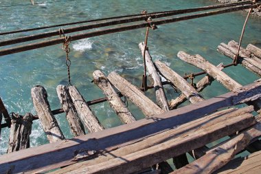 Abhazya'da güneşli bir sonbahar gününde dağ nehri Bzıb uzun yaya asma köprü. Gürcistan.
