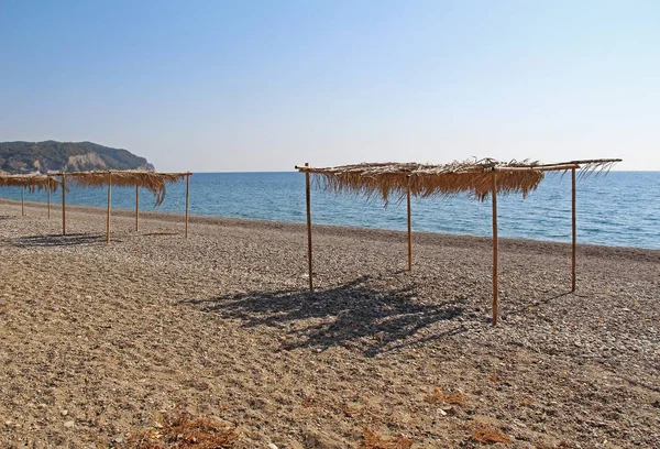 Costa del Mar Negro con refugios de bambú del sol en un día de verano. Abjasia . — Foto de Stock
