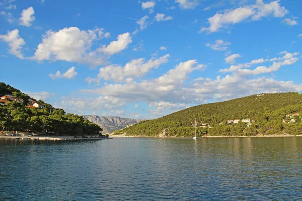 A yacht entering the bay by the town. Pucisca is small town on Island of Brac, Croatia. — Stock Photo, Image