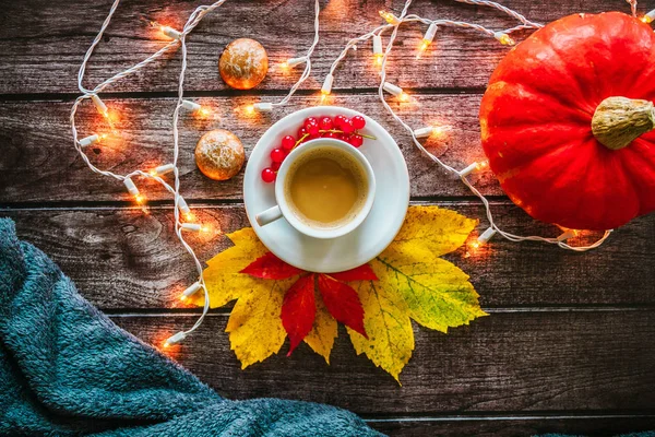 Sonbahar natürmort: fincan kahve, kurabiye, aydınlık garland, ekose, sarı ve kırmızı bir ahşap arka plan üzerinde bırakır. Çekim nesne. 