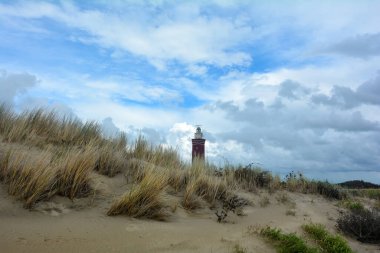 Hollanda 'nın Ouddorp kentinde, Avrupa' nın Zeeland kentinde, ön planda plaj çimleri bulunan 56 metre yüksekliğindeki 