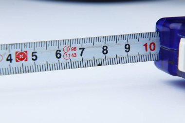 Evde ya da işte beyaz arka plan üzerinde bazı uzunluğu ölçmek için küçük bir şerit metre