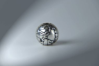 Gri arka plan üzerinde gümüş bir mücevher. Dünya gezegeni inanılmaz zinciri aksesuar olarak. Kız arkadaşım için hediye