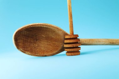 Casual tahta kaşık bazı sosu veya başka bir yiyecek ve kaşık bal karıştırarak için. Mavi arka plan