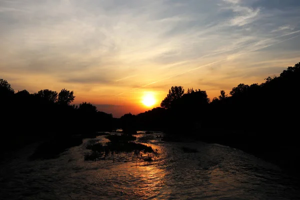 A our sun lighting river. Sky playing with many colours. From blue to red. Beautiful evening