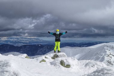 Erkek kayakçı taş üzerinde duran ve dağın tepesinden Vadisi arıyorum. Düşük Tatras, Chopok. Bedava yolculuk. Bir kayakçı arasındaki sınırda duruyor. Bulutlu gökyüzü. Yüksek Tatras görünümü