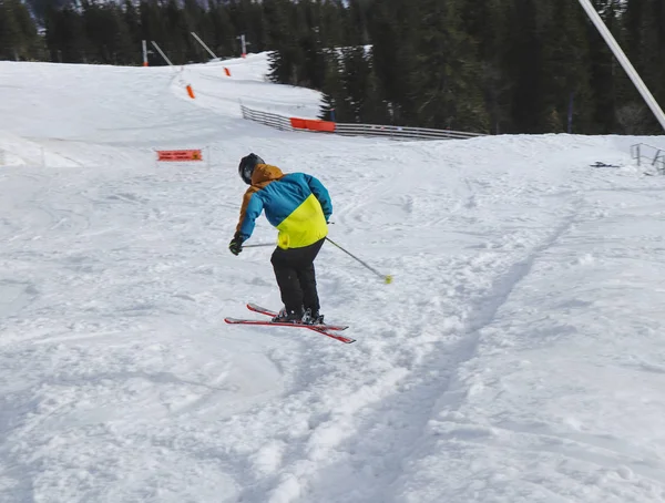 Niño esquiador realiza un salto de altura con el esquí en Chopok, Eslovaquia. Temporada de invierno, chaqueta colorida. Niño pequeño saltando en esquís cuesta abajo. Gran salto —  Fotos de Stock