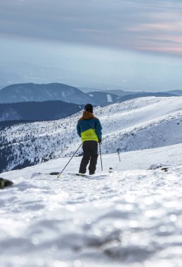 Bir çocuk bir çapraz üzerinde kayak kayakçı. Bir çocuk yokuş aşağı ikinci parçası almak gerekir. Kayakçı kolay olacak ve yavaş Kayak yapıyor. Düşük Tatras, Slovakya görünümü. Panoramik yokuş aşağı. Günbatımı.