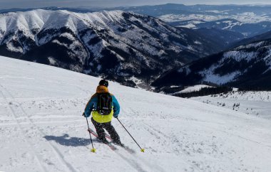 Erkek kayakçı Kayak freeride yokuş aşağı Oda için Vadisi düşük Tatras, Slovakya. Renkli ceket siyah sırt çantası ile