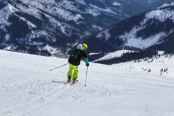 Boy is turning on other side for next arc on skies. A male skier skiing freeride in Slovakia mountains, Low Tatras. Yellow helmet. Ski poles — Stock Photo, Image