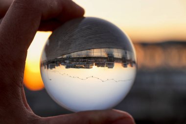 Günbatımında Limasol 'un limanında kristal küre. Cam / Lens topu arka planda altın şehir ışıkları ve denizle el ele tutuşarak günbatımında Limasol şehrini yansıtıyor. Kıbrıs