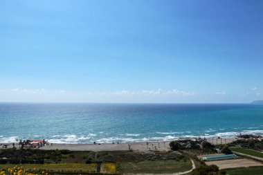 Mavi gökyüzü ve kıyıda ortalama dalgalar ile blu deniz. Çok keskin güneşte Kourion plajında görünümü. Güney Kıbrıs'ta büyük plaj, sörfçüler ve su sporları için ideal