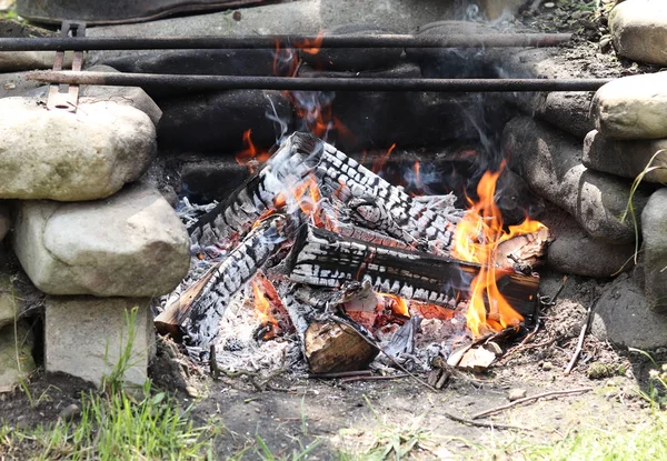 Uitgebrande logs in zelfgemaakte kampvuur creëerden voornamelijk ovale steen. Vuur is klaar voor het bakken van vlees. Sintels. Buiten casual uitzicht. Garden Relax — Stockfoto