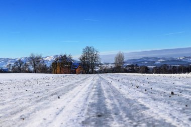 Çek Cumhuriyeti'nde Beskydy dağlarının eteklerinde çakıl serpilir donmuş orman yolu. Tipik kış günü. Kırsal manzara. Muhteşem kar örtüsü.