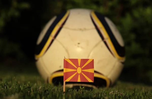 Weltmeisterschaft 2022. euro 2020. mazedonische Fahne auf dem Fußballplatz mit weißem Ball. Nationalflagge der mazedonischen Sonne auf Papier mit rotem Hintergrund. — Stockfoto
