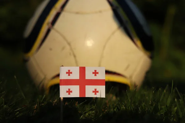 格鲁吉亚国旗在木棍上刺伤在足球场和背景经典足球。2022年世界锦标赛。2020年欧元 — 图库照片