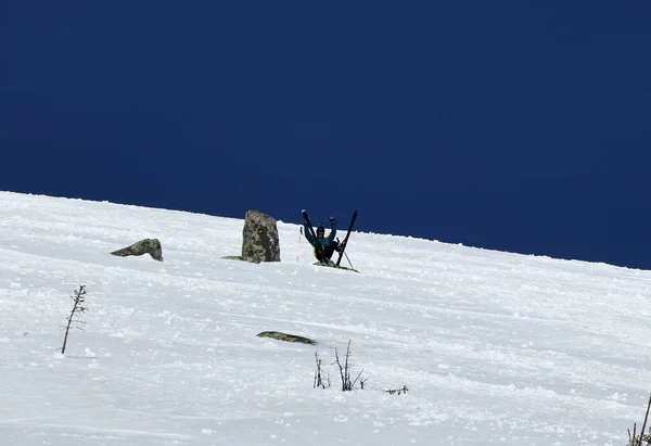 Skieur professionnel vêtu de vêtements sombres se détendre avant de monter. Free rider est assis sur la neige sur le sommet de Chopok situé à Low Tatras en Slovaquie. Peu de repos après une dure journée de travail. Contraste neige blanche et ciel — Photo