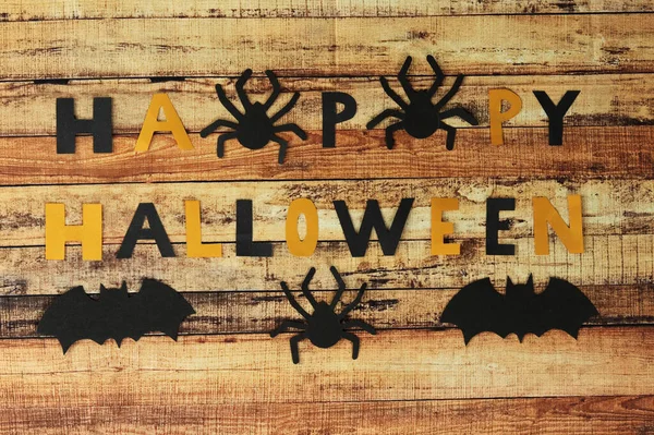 Decoração de Halloween com muitas aranhas pretas e morcegos. Fundo é baseado em tábua de madeira. Ornamentos assustadores com inscrição Halloween composto por letras pretas e amarelas — Fotografia de Stock