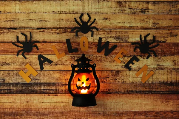 Decoração aterradora em feriado de outubro famoso como Halloween. Letras pretas e amarelas compostas para o Halloween com aranhas ao redor. Lâmpada brilhante com rosto horrível — Fotografia de Stock