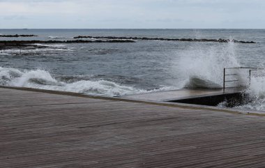 Güçlü rüzgarla birlikte kıyıların duvarlarına çarpan ve her yöne doğru kırılan dev dalgalar geldi. Köpüklü deniz. Denizin gücü. Doğa ananın gücü. Yağmurlu bir hava. Paphos, Kıbrıs.