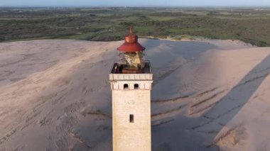 Tepenin tepesinde ünlü deniz feneri olan dev kum tepelerinin hava manzarası. Rubjerg Knude Deniz Feneri, Kuzey Deniz Rubjerg, Danimarka Lokken yakınlarındaki Rubjerg Knude Fyr deniz fenerinde gün batımı. 