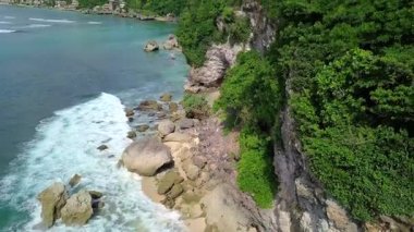 Günbatımında, Endonezya, Bali 'de, turkuaz dalgalı bir deniz tarafından yıkanan güzel adanın göz kamaştırıcı manzarası. Endonezya 'da yaz günü mavi gökyüzünün altındaki dağlara karşı plantasyonlar