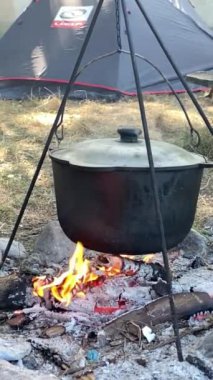 Kamp çadırının yanındaki açık ateşte yemek pişirmek için bir kazan.