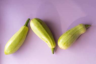 Açık mor arka planda üç yeşil kabak, sağlıklı yemek.