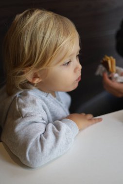 Three-year-old boy being fed junk food at the table