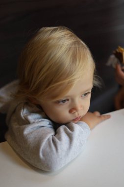 Three-year-old boy resting his head on his hand at the table in a restaurant