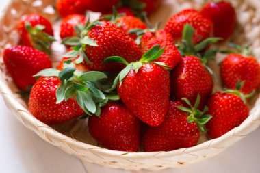 Olgun kırmızı çilek bir hasır sepet beyaz rustik ahşap arka plan üstten görünüm üzerinde yalan