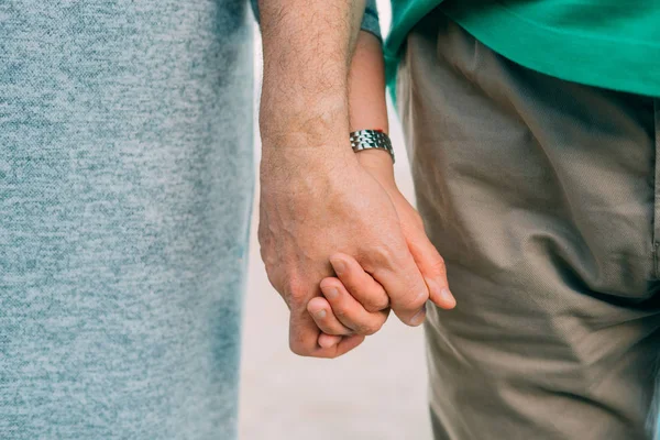 Yaşlı bir çift elele sıkıca kum arka planı