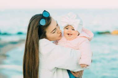 Anne ile kızı kumsalda oynarken. Anne kızını sarılma.