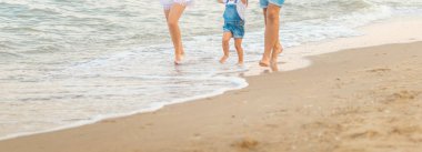 Üç - güzel karısı, baba ve kız eğleniyor mutlu aile yakın gün batımında sahilde yürüyüş. Aile kavramı seyahat. yaz günü