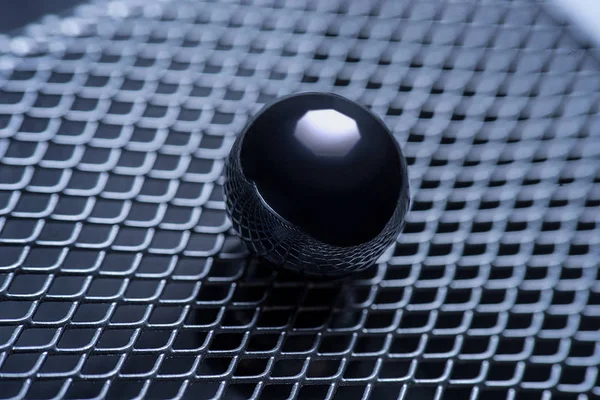 macro photo. metal ball on the background of iron grating, side view