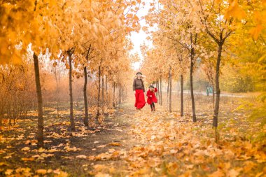 Genç Anne küçük kızıyla birlikte sonbahar bahçe genel planı çalış.