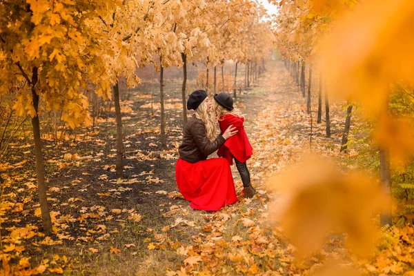 young mother plays with her little daughter in the autumn garden overall plan