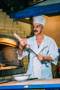 Beyaz üniformalı cook et mangal kömürleri ile bir arka plan üzerinde bir şiş üzerinde şeritler