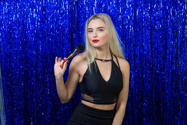 Sexy fille styliste maquillage artiste posant amusant à la caméra avec une grande brosse douce pour le maquillage sur un fond bleu brillant — Photo