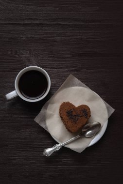 bir ahşap eski arka plan üzerinde beyaz bir daire hoş kokulu kahve yanında kalp şeklinde çikolata tatlı duruyor
