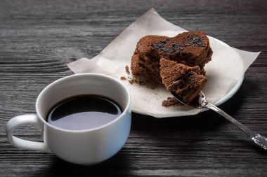 bir ahşap eski arka plan üzerinde beyaz bir daire hoş kokulu kahve yanında kalp şeklinde çikolata tatlı duruyor