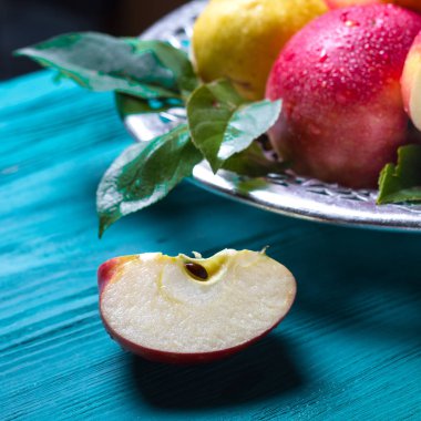Kırmızı sulu elma bir parça bir mavi ahşap masa soruda bu tabak meyve ile yatıyor