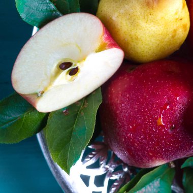 Olgun kırmızı elma ve sarı armut masaya bir tabak içinde yalan