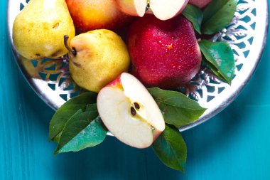 Olgun kırmızı elma ve sarı armut masaya bir tabak içinde yalan