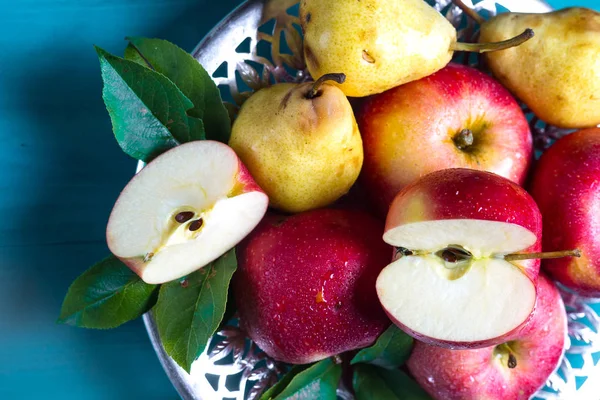 Olgun kırmızı elma ve sarı armut masaya bir tabak içinde yalan