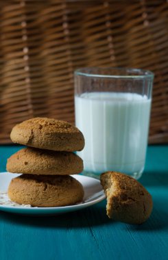 Bir tabak ve bardak süt bir ahşap zemin üzerine yulaf ezmeli kurabiye