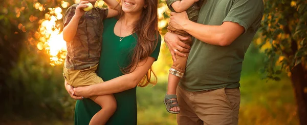 Concept family park vacation. A family of four mum, father holding his son, parents holding a childs hand walkingat sunset — Stock Photo, Image