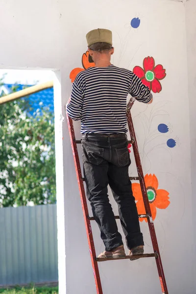 Homem Pinta Pinta Uma Parede Branca Com Ornamentos Florais Verão — Fotografia de Stock