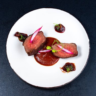 Beyaz tabakta orta pişmiş fileminyon biftek, seçili üst görünüm